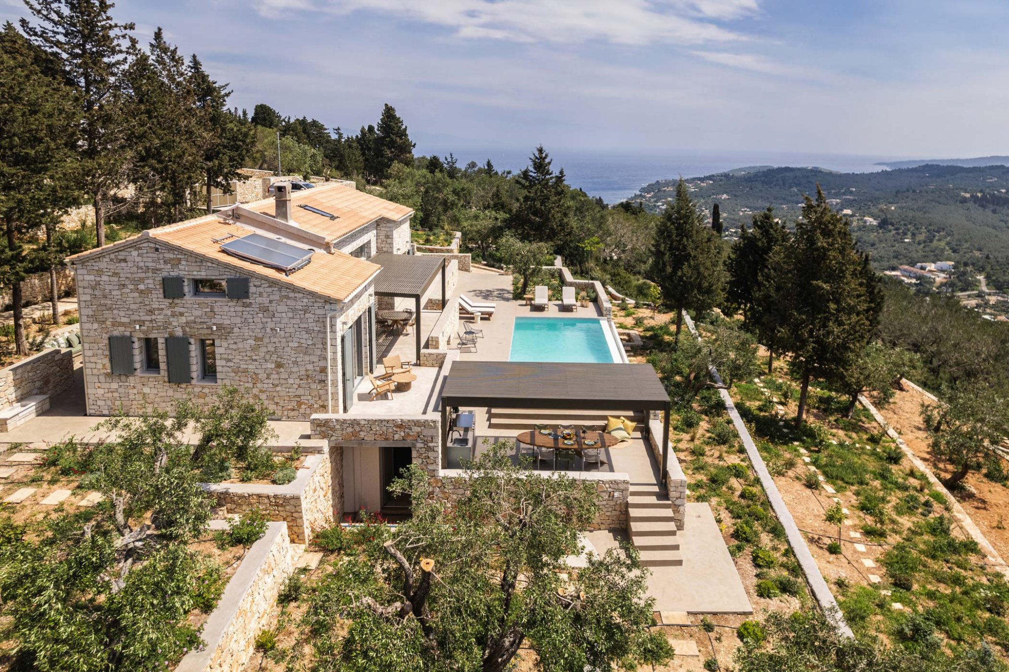 Aerial view of the stone villa Bacchetta Magica and its pool among olive groves