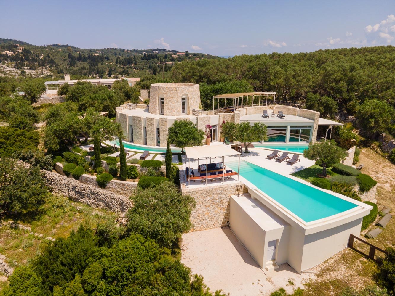 Aerial view of the curved stone villa Pax and its long pool